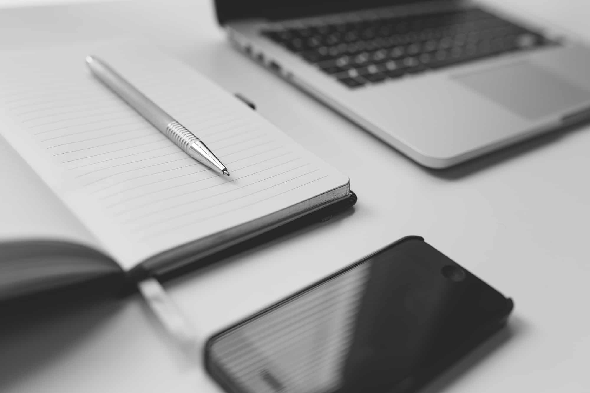 Notebook, laptop and phone on a desk